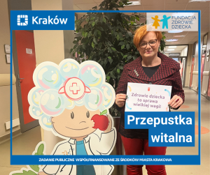 Na szpitalnym korytarzu stoi rysunkowa postać doktorka Ludwiczka. gryzącego jabłko. Napis: przepustka witalna